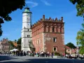 Ratusz w Sandomierzu z zegarem i zegarem słonecznym. Spacerujący ludzie na rynku, ciekawe miejsca Sandomierza.