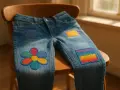 Jeans con applicazioni colorate: un fiore, un arcobaleno e quadrati decorativi, realizzati con il punto rammendo.