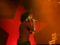 Zac Zack de la Rocha śpiewa z pasją na koncercie Rage Against the Machine. Czerwona gwiazda w tle podkreśla energię występu.