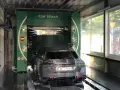 Jak korzystać z myjni automatycznej: samochód w trakcie mycia, obficie spieniony, z obracającymi się szczotkami.