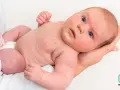 Niemowlę z widoczną wysypką alergiczną na twarzy i ciele. Czerwone plamki pokrywają skórę, wskazując na reakcję alergiczną u dziecka.