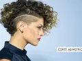 Mujer con pelo corto rizado y rapado asimétrico, luciendo un estilo audaz y moderno.