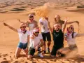 Grupa przyjaciół w tradycyjnych arabskich chustach bawi się piaskiem na pustyni. Wspaniałe wspomnienia z Dubaju w styczniu.