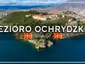 Widok na Jezioro Ochrydzkie z górami w tle, miastem na wzgórzu i twierdzą.