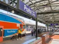 Pociąg z Gdańska do Pragi na dworcu głównym. Mężczyzna w żółtej kurtce z rowerem czeka na peronie.