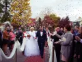 Para młoda idzie po czerwonym dywanie, obsypana płatkami. Piękny ślub w październiku, jesienne drzewa w tle.