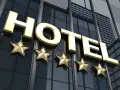 Złote litery "HOTEL" i pięć gwiazdek na nowoczesnym budynku. Spełnia hotel 4 gwiazdki wymagania luksusu i komfortu.