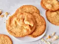 Saftige white chocolate cookies, eine davon angebrochen, mit Stückchen weißer Schokolade und Krümeln daneben.