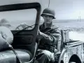 Elvis Presley in seiner US Army Uniform, sitzt am Steuer eines Jeeps.
