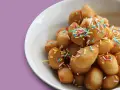 Un piatto di dolci tipici pugliesi, piccole palline dorate cosparse di zuccherini colorati, invitano a un assaggio di tradizione.