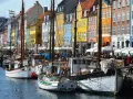 Colorful buildings line a canal in Copenhagen, with boats docked and people enjoying the waterfront. A perfect scene for exploring things to do in Denmark.
