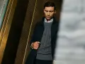 Elegancki mężczyzna w szarym swetrze męskim z warkoczowym splotem, pod ciemną marynarką. Stylowa inspiracja, jak nosić sweter męski.
