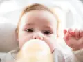 Urocze niemowlę pije mleko z butelki. Ważne, by mleko miało odpowiednie ile stopni mleko dla niemowlaka, by było bezpieczne i smaczne.