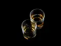 Dwa szklanki z bursztynowym płynem, idealne na wieczór z drinkiem. Czy to Baileys?
