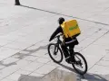 Kurier Glovo na rowerze z charakterystyczną żółtą torbą. Praca w dostawie to jego codzienne wyzwanie.