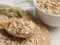Płatki owsiane na drewnianej łyżce i w misce. Czy płatki owsiane mają gluten? Czysty owies jest bezglutenowy, ale warto sprawdzić etykietę.