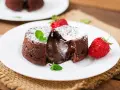 Pyszny fondant czekoladowy z płynnym środkiem, przypominający małe soufflé czekoladowe, podany z truskawkami i miętą.