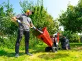 Mężczyzna w ochronnych słuchawkach i okularach przygotowuje się, by wrzucić gałęzie do rozdrabniacza Cedrus. To prosty sposób, jak rozdrobnić gałęzie.