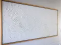 Peinture relief sur toile, texture blanche texturée évoquant des vagues douces dans un cadre en bois.
