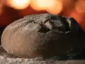 Ein Laib Brot liegt auf einer bemehlten Holzschaufel, bereit für den Ofen. So gelingt energiesparend Brot backen.