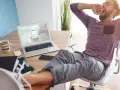 Hombre bosteza en su escritorio, con los pies en alto. Sabe que tengo derecho a un fin de semana libre al mes, ¡y lo ha ganado!