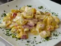 Tortellini panna e prosciutto, un classico piatto italiano, serviti su un piatto bianco con prezzemolo tritato.
