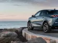 Nowy Peugeot 3008 hybryda na tle spokojnego morza i skalistego wybrzeża.