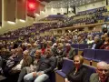 Widownia filharmonii, ludzie w eleganckich strojach. Jak się ubrać do filharmonii mężczyzna? Garnitur lub marynarka to dobry wybór.