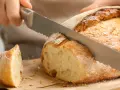 Krojenie świeżo upieczonego, domowego chleba. Ten przepis na chleb domowy pieczony w piekarniku jest idealny na każdą okazję.