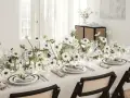 Ett elegant dukat bord med vita anemoneblommor och kristallglas. En diskret detalj är sugrör guld som ger en lyxig touch.