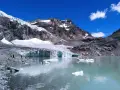Un lago glaciale riflette montagne imponenti e il ghiacciaio Fellaria, con iceberg che galleggiano sull'acqua turchese.
