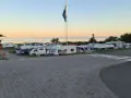 Solnedgång över Lerbergets camping med husbilar och husvagnar uppställda. En svensk flagga vajar i vinden.