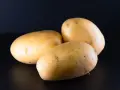 Trzy ziemniaki na czarnym tle. Czy można jeść ziemniaki przed kolonoskopią? Zazwyczaj nie zaleca się spożywania ziemniaków przed kolonoskopią.