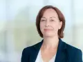 Agata Witkowska, aktorka, w granatowej marynarce i białej bluzce, uśmiecha się lekko.