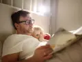 Vater im Elternzeit, 1 Monat alt, liest seinem Kind im Bett eine Geschichte vor.