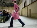 Modello sfila con trench rosa e pantaloni blu, un esempio di moderno stile uomo.
