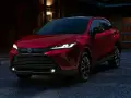 Elegancka, czerwona Toyota Venza z nowoczesnymi światłami LED stoi przed domem o zmierzchu.
