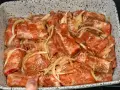 Babcine żeberka w sosie własnym, gotowe do pieczenia. Mięso w sosie z cebulą, przyprawione ziołami, w naczyniu żaroodpornym.