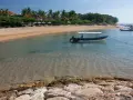 Spokojna zatoka w Sanur na Bali, z łodzią "Water Walk" kołyszącą się na turkusowej wodzie, plażą i palmami w tle.