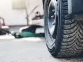 Opony kierunkowe z bieżnikiem zapewniającym przyczepność na śliskiej nawierzchni. W tle zielony podnośnik samochodowy.
