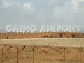 Ogromne białe litery "CAIRO AIRPORT" na tle pustynnego krajobrazu. Jedno z lotnisk w Egipcie.