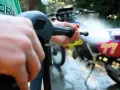 Mani che impugnano un'idropulitrice per pulire una moto da cross. Un modo efficace per capire come lucidare la moto.