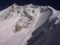 Schneebedeckte Gipfel des Huayna Potosí, mit steilen Eiswänden und felsigen Hängen unter einem tiefblauen Himmel.