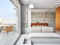 Habitación con diseño industrial, cama baja, sofá de lino y terraza con ducha exterior.