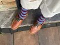 Pies con calcetines a rayas azul y burdeos y mocasines de cuero marrón. Un ejemplo de cómo combinar color teja ropa con estilo.