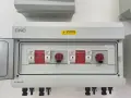 Biała skrzynka elektryczna z czerwonymi przełącznikami i numerowanymi slotami.