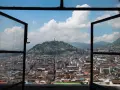 Widok na miasto z otwartego okna, z wzgórzem i pomnikiem w tle. To piękna panorama stolicy Ekwadoru, ze stolicą w Quito.