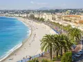 Spiaggia di Nizza, un luogo ideale per pensare a come trovare lavoro all'estero, con palme e mare azzurro.