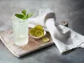 Orzeźwiający mojito z ginem, udekorowany miętą i podany z plasterkami limonki na drewnianej desce.