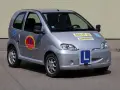 Srebrny samochód do nauki jazdy, kategoria B1. Z przodu i z boku widoczne litery "L", a na drzwiach okrągłe logo szkoły jazdy.